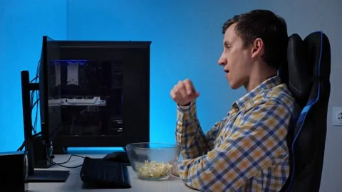 Young man watches stream with computer and eats popcorn Video stock 165032399
