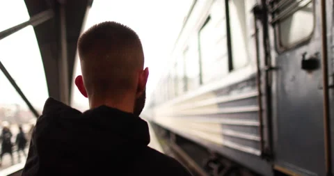 A young man watches a train leave the station. Stock Footage 247353787