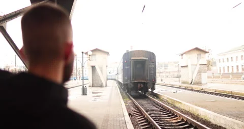 A young man watches a train leave the station. Stock Footage 247353936