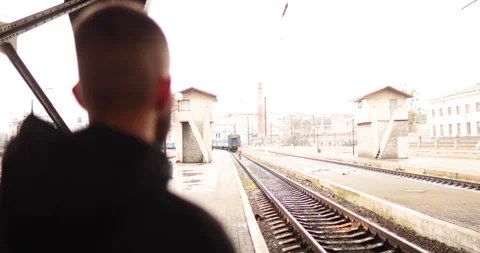 A young man watches a train leave the station. Stock Footage 247353983