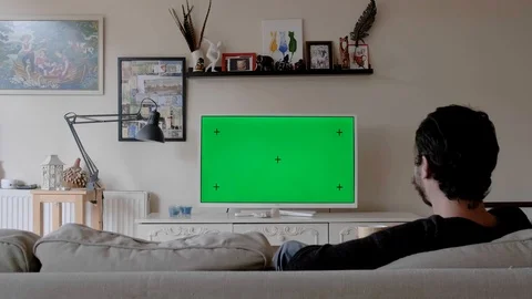 A Young Man Watches A Tv With A Green Screen In A Living Room Stock Footage