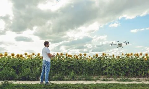 Young man watching and navigating a flying drone in blue clear sky Stock Photos