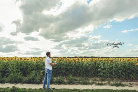 Young man watching and navigating a flying drone in blue clear sky Stock Photos