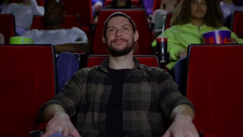 A young man is watching a good comedy at the cinema in a slow medium shot, a 库存影片 267349840