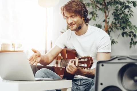 Young man watching guitar tutorial on his laptop 写真素材