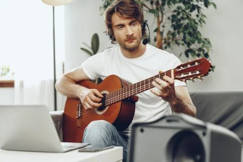 Young man watching guitar tutorial on his laptop Foto stock