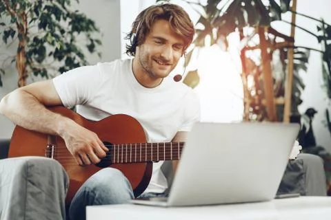 Young man watching guitar tutorial on his laptop Foto stock