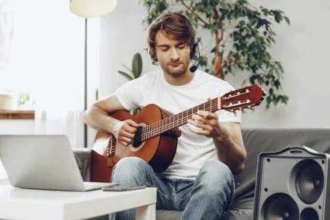 Young man watching guitar tutorial on his laptop 스톡 사진