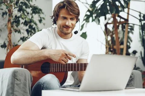 Young man watching guitar tutorial on his laptop Foto stock
