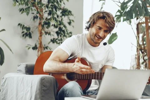 Young man watching guitar tutorial on his laptop 写真素材