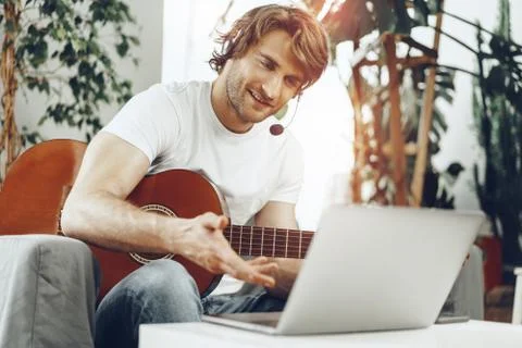 Young man watching guitar tutorial on his laptop Foto stock