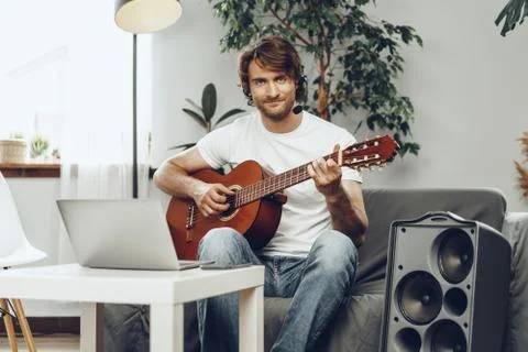 Young man watching guitar tutorial on his laptop Foto stock