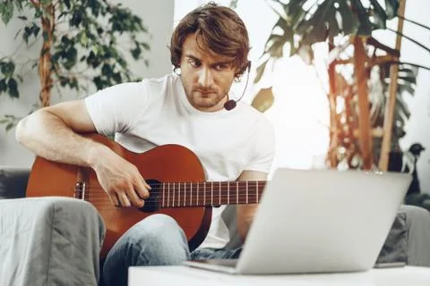 Young man watching guitar tutorial on his laptop 写真素材