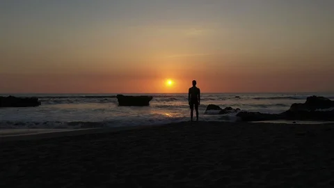 Young Man Watching Sunset While Waves Crash Stock Footage 120131931