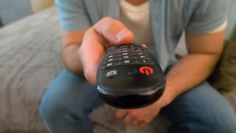 Young man watching TV and changing channels with remote control Stock Footage 323921269