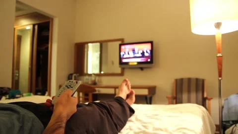 mladý muž pozerá televíziu v hotelovej izbe