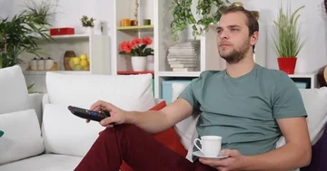 Young Man Watching TV While Drink Hot Coffee Laying Modern Sofa in Living Room Stock-Footage 85474158