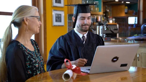 Young man watching virtual commencement ceremony on laptop computer switches Stock Footage 128978381
