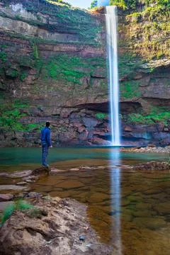 Young man at waterfall falling streams from mountain top with reflection from 写真素材