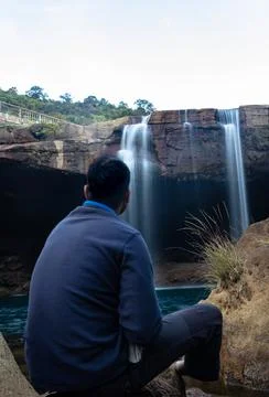 Young man with waterfall streams falling from mountain top at morning long ex Fotos de archivo