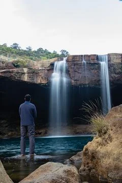 Young man with waterfall streams falling from mountain top at morning long ex Fotos de archivo