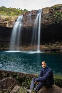 Young man with waterfall streams falling from mountain top at morning long ex Stock Photos