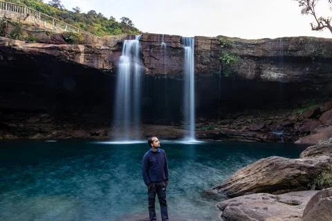 Young man with waterfall streams falling from mountain top at morning long ex Foto stock