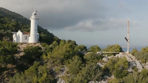 A young man waving in the background of lighthouse. Natural landscape. Video stock 133081540