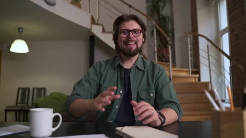 Young man waving in front of device and sitting at table in home office spbas. Stock Footage 166837897