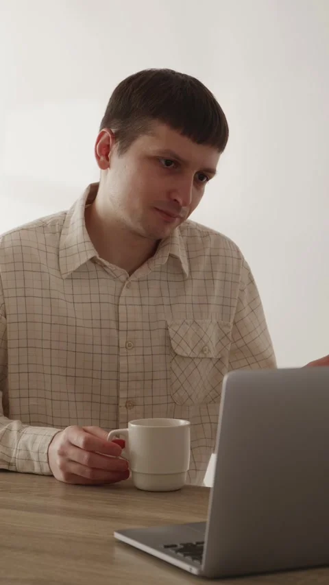 Young man waving hand during video conference call on laptop at home 스톡 동영상 335082322