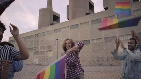 Young man waving a rainbow flag in a gay parade. Group of people participating Stock Footage 207237915