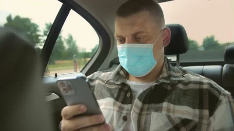 Young man wear mask using smartphone to type a message while sitting Stock Footage 201086663