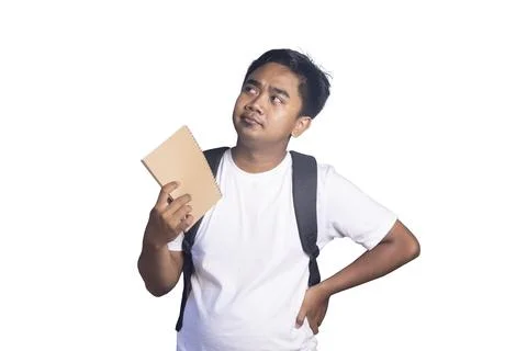 Young man wearing a backpack and holding a notebook while looking up with a.. Stock Photos