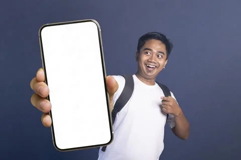 Young man wearing a backpack and pointing excitedly at a large smartphone w.. Stock Photos