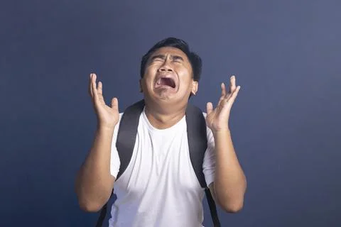 Young man wearing a backpack crying out in frustration and despair with han.. Stock Photos