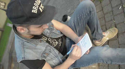 A young man wearing a cap in the notebook draws a graph and figures. Stock Footage 51755121