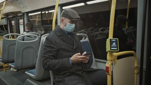 Young man wearing face mask comming back from work late by bus using smartphone Stock Footage 168622015