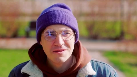 Young man wearing glasses drinking coffee in the spring park. Close-up shot. Vídeos de archivo 256962072