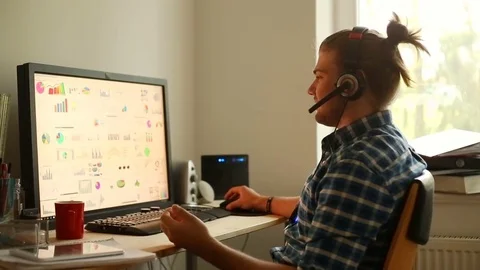 Young man wearing headset and talking with someone in the home office Stock Footage 75150112