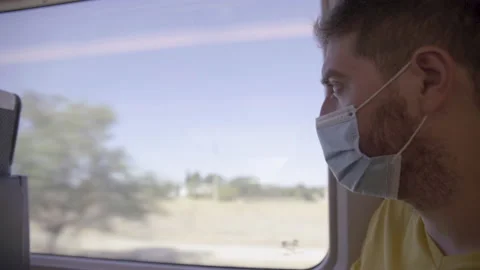 Young man wearing medical mask looks thru the  train´s window Stock Footage