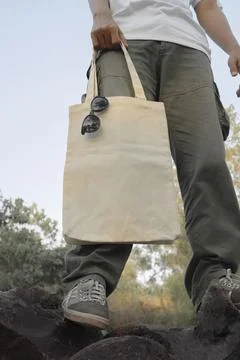 Young man wearing a plain white t-shirt holding a clean white tote bag. Cle.. Stock Photos