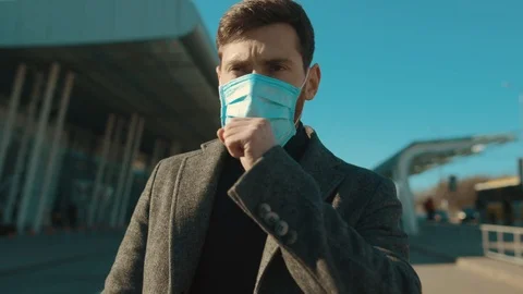 Young man wearing Protective Face Mask walk near airport with suitcase coughs Stock Footage 126619087
