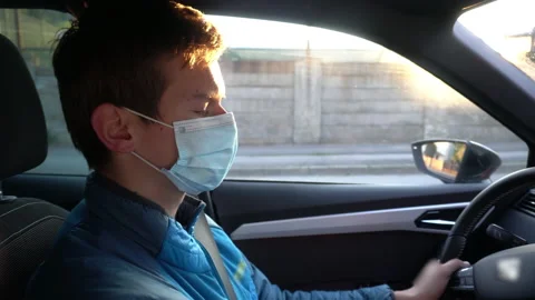 Young Man Wearing Protective Face Mask while Driving Car From Work - Coronavirus Stockbeeldmateriaal 131048565