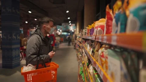 Young man wearing protective face mask shops in grocery store. Male customer in Stock Footage 150982699