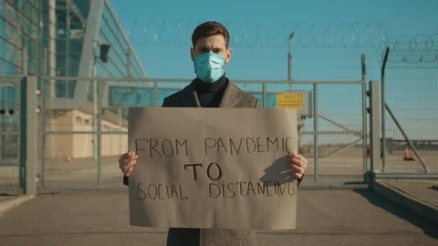 Young man wearing protective mask on street hold poster from pandemic to social Stock Footage 126582420