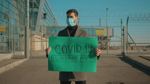 Young man wearing protective mask on street hold poster COVID-19 is a global Stock-Footage 126584481