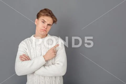 Young man wearing sweater studio isolated on grey pointing aside thoughtful Stock Photos