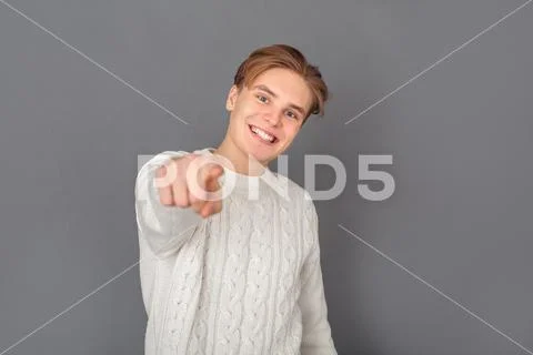 Young man wearing sweater studio isolated on grey pointing at camera Stock Photos