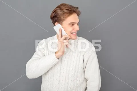 Young man wearing sweater studio isolated on grey talking on phone happy Stock Photos