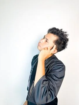 A young man wearing a traditional-patterned black robe gestures with his in.. Stock Photos